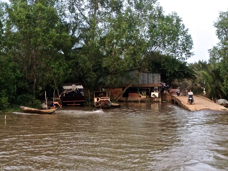 Kids playing in boats and riding motorbike along the Mekong Delta in Southern Vietnam