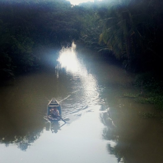 Man paddling his rowboat along the Mekong Delta in South Vietnam